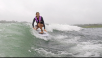 a smiling lady wakesurfs on lake arenal trying to keep balance
 - Costa Rica