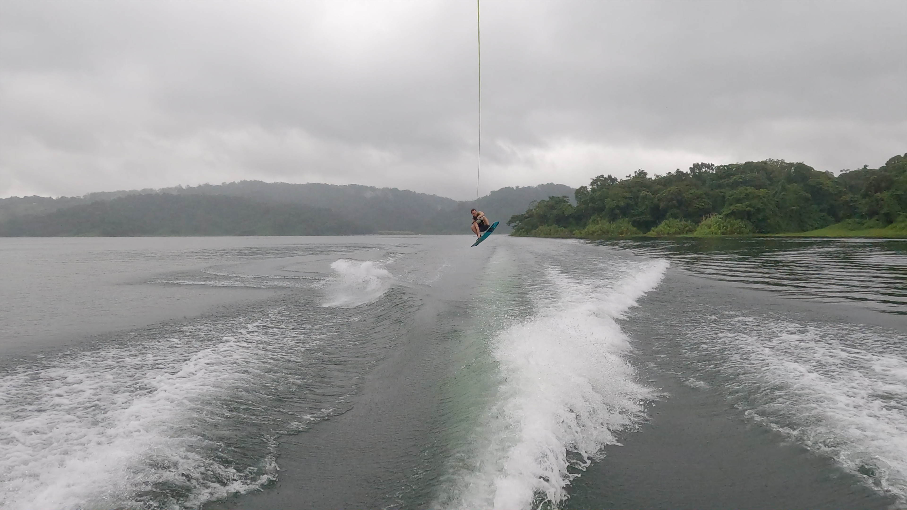 a man wakeboards jumping in the air above lake arenal on a foggy morning.jpg