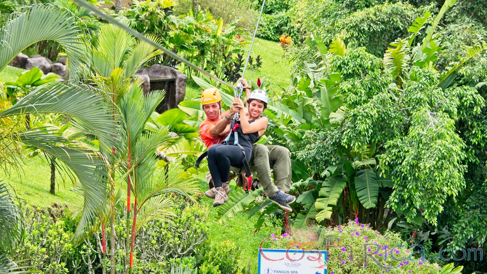 Lady Riding The Cable With A Guide Above The Resort Los Canones Canopy Tour La Fortuna