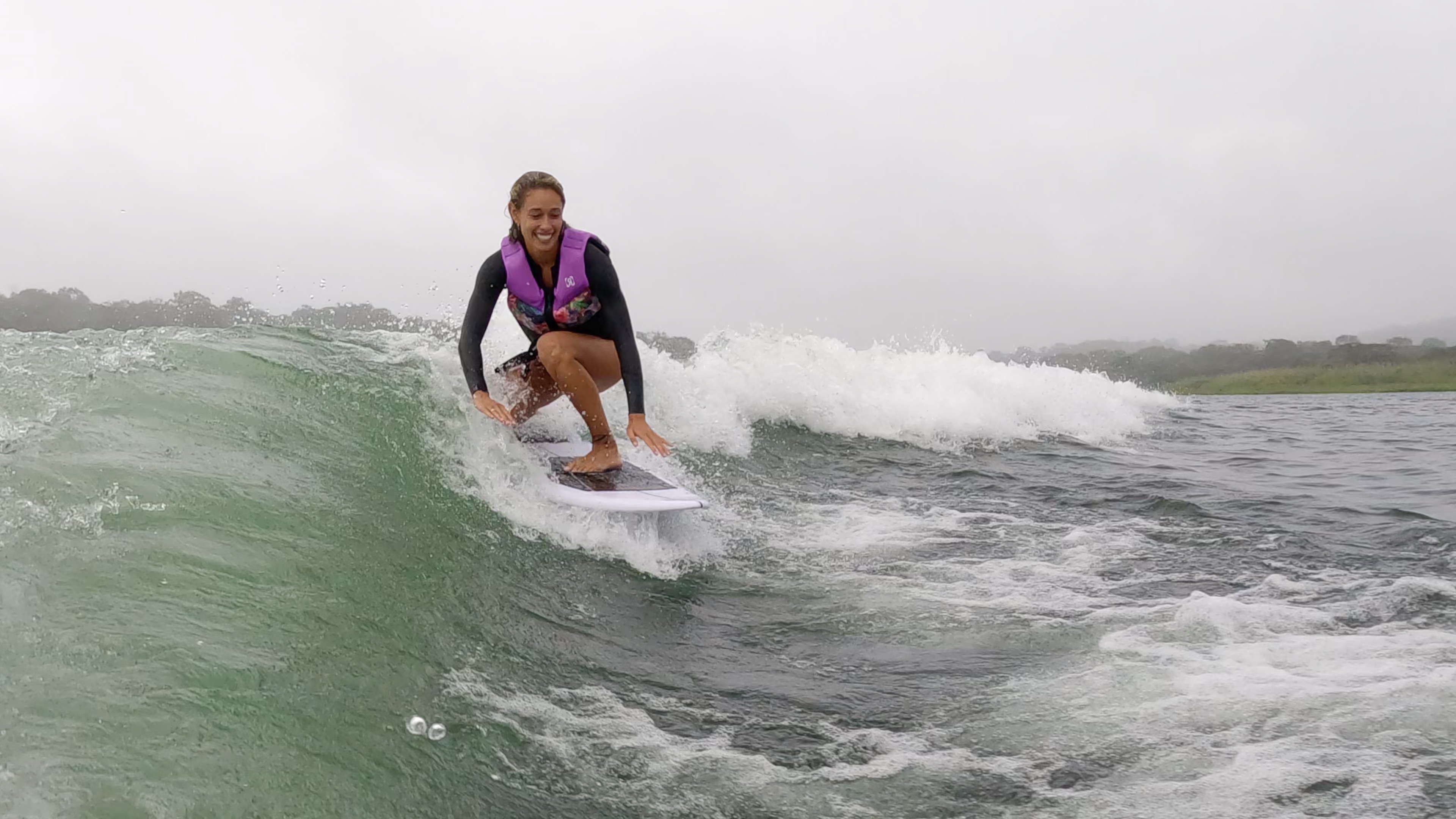 a smiling lady wakesurfs on lake arenal trying to keep balance.jpg